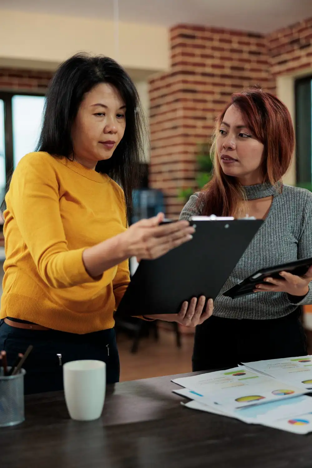 Two women in an office engaged in a discussion, sharing ideas and collaborating on a project.
