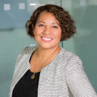 A woman with short hair and a black top smiling warmly.