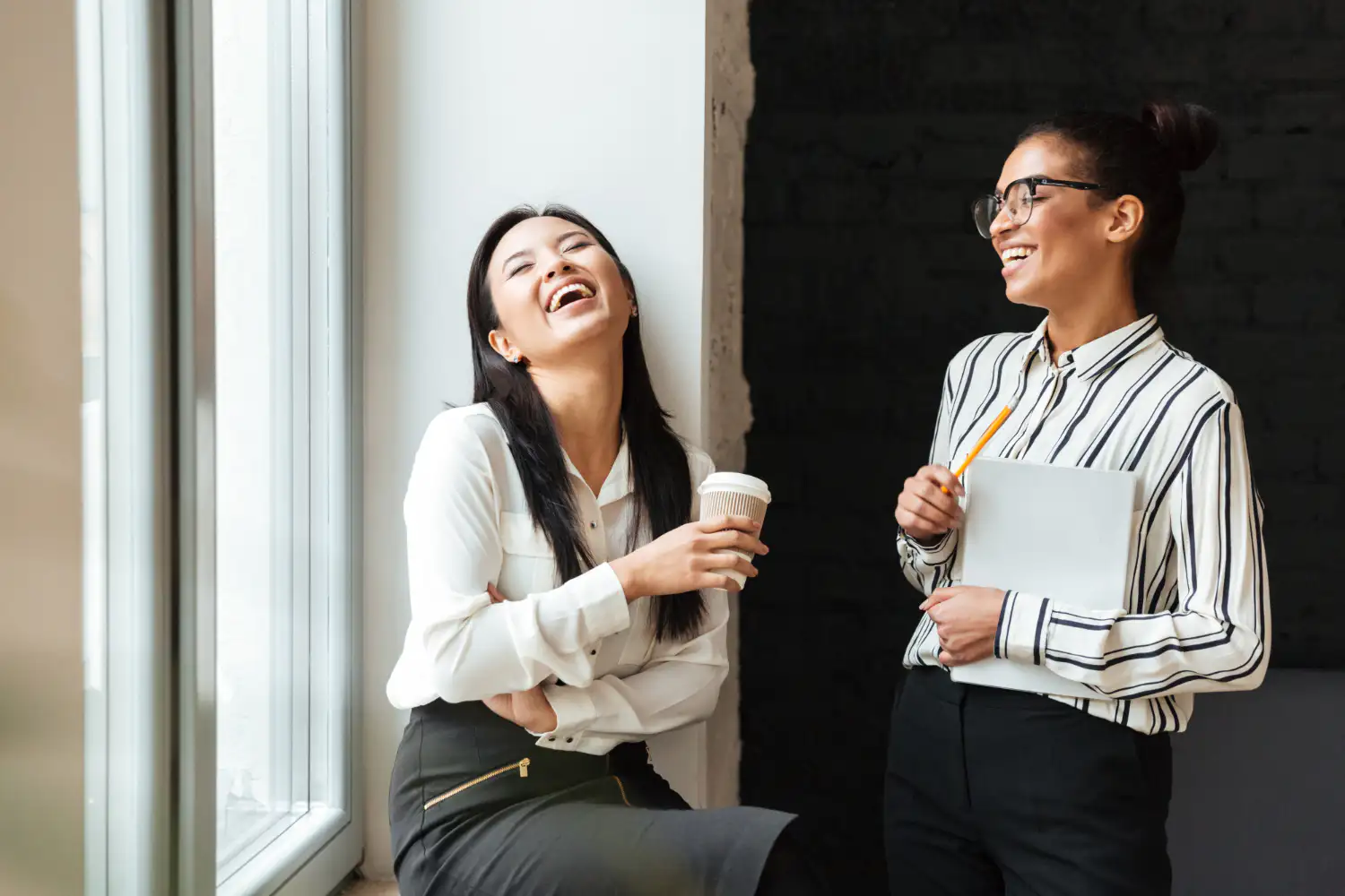 Two women enjoying a cup of coffee together, sharing a moment of laughter and joy.